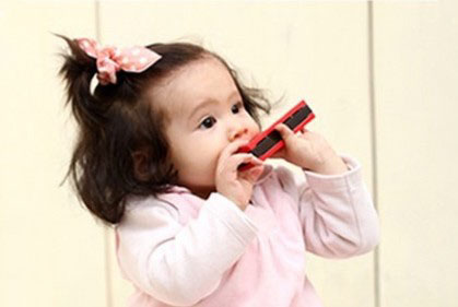 Kind dat op de houten harmonica speelt en spelenderwijs de ademhaling stimuleert
