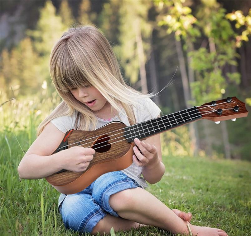 Kind dat speelt op de akoestische houten Montessori-gitaar met nylon snaren