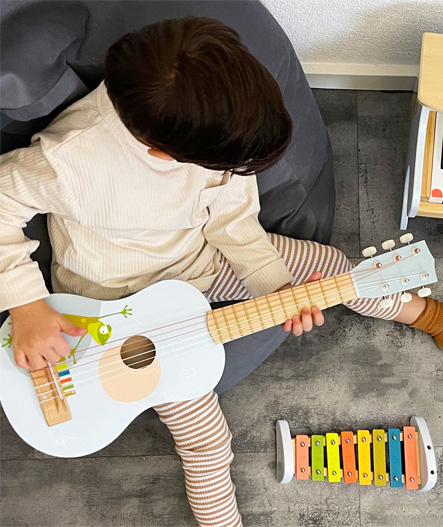 Jong kind dat speelt op de houten akoestische Montessori-gitaar